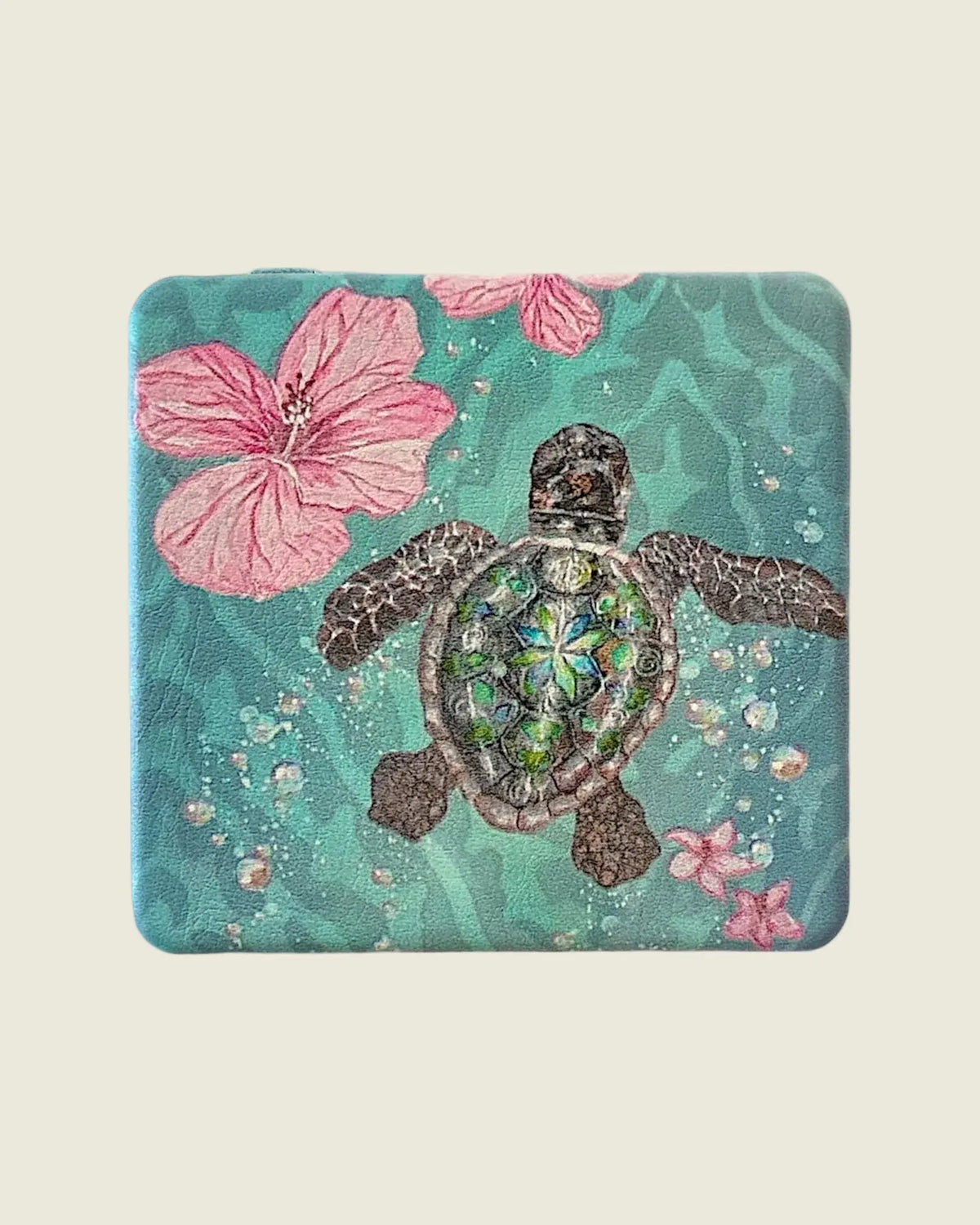 Vue rapprochée du miroir de poche fermé, avec tortue marine, hibiscus roses et étoiles de mer sur fond turquoise
