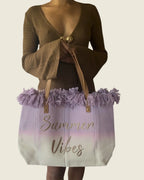 Sac cabas Summer Vibes lilas et écru à franges, porté devant une robe marron