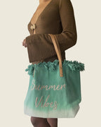 Sac cabas Summer Vibes vert dégradé à franges, porté au bras avec une robe marron