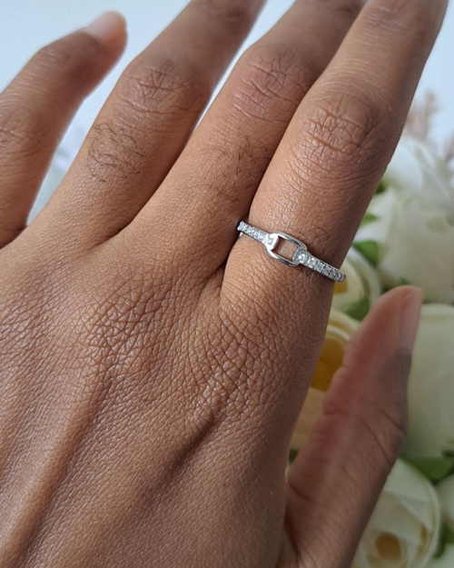 Bague strass argentée portée au doigt devant des fleurs blanches – bague fine zirconium femme