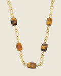 Collier chaîne dorée à maillons avec perles rectangulaires en œil de tigre marron et ambré, fond noir