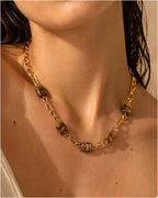 Collier chaîne dorée avec perles en œil de tigre porté par une femme, style naturel beach-luxe