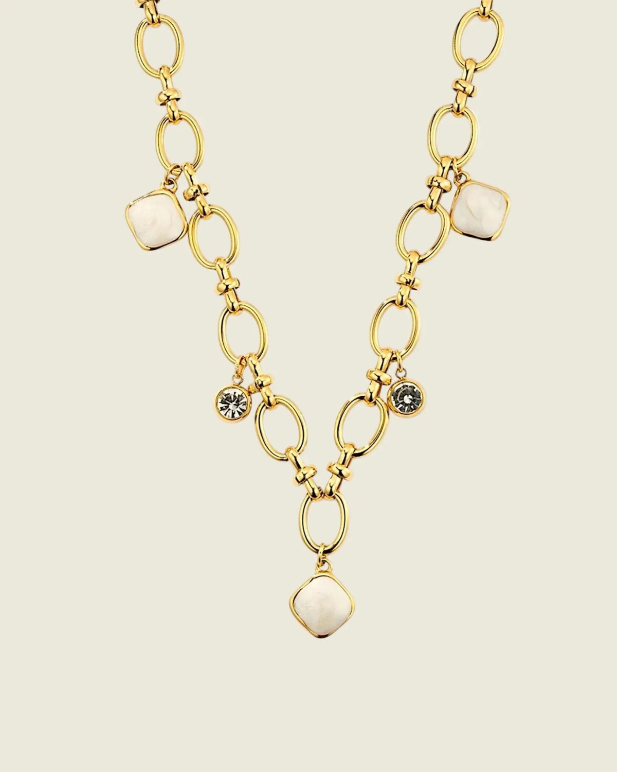 Collier chaîne dorée à maillons porté sur une femme, avec pendentifs en pierre de lune blanche et cristaux, style beach-luxe