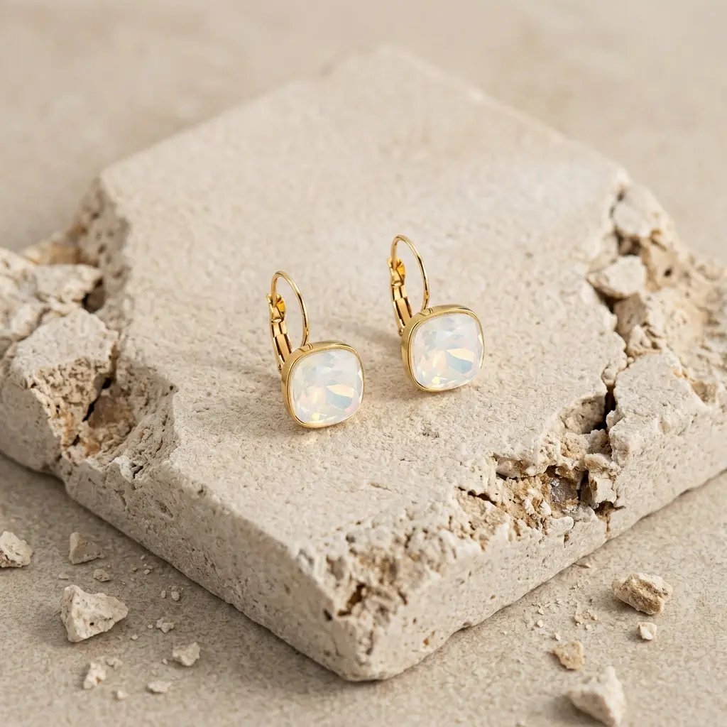 Boucle d'oreille dorée à cabochon carré en nacre blanche portée par une femme aux cheveux bouclés