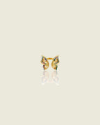 Bague ouverte dorée en forme de papillon, ornée de pierres multicolores, sur fond beige avec reflet.
