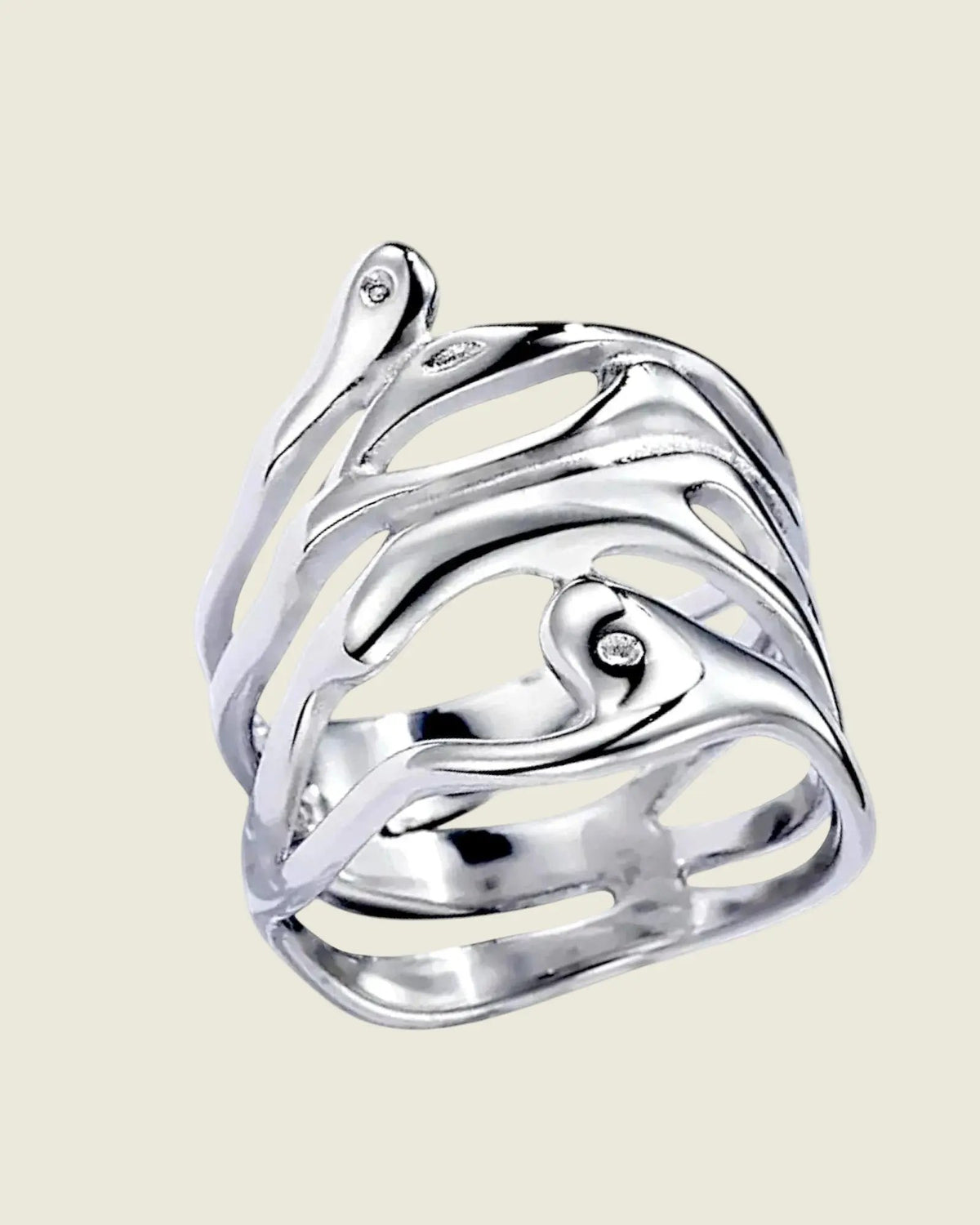 Gros plan de la bague large ajourée en acier inoxydable argenté, montrant son design organique sur fond beige clair