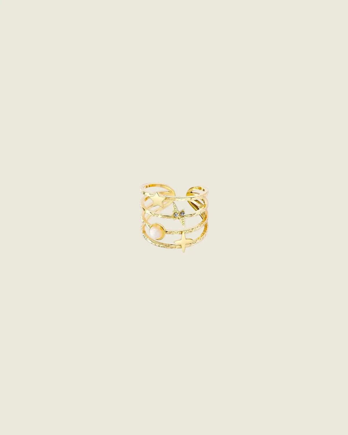 Bague astrale ouverte en acier inoxydable doré, montrant ses rangs fins et ses motifs étoilés sur fond beige clair