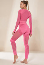 Ensemble de sport rose porté de trois quarts dos, montrant les empiècements rayés du top et du legging taille haute.
