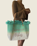 Sac cabas Summer Vibes vert clair et écru à franges, porté au bras avec une robe marron