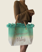 Sac cabas Summer Vibes vert clair et écru à franges, porté au bras avec une robe marron