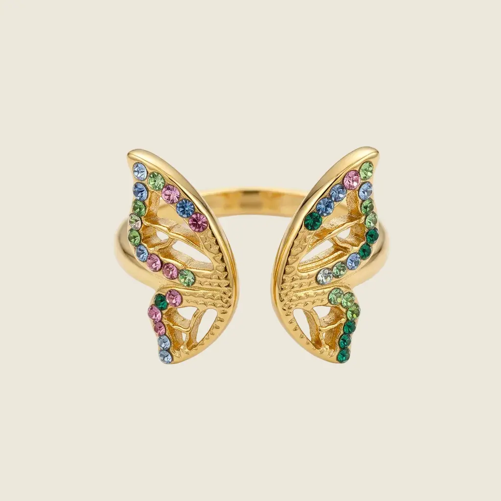 Gros plan de la bague papillon dorée, montrant les ailes ajourées serties de pierres roses, bleues et vertes.